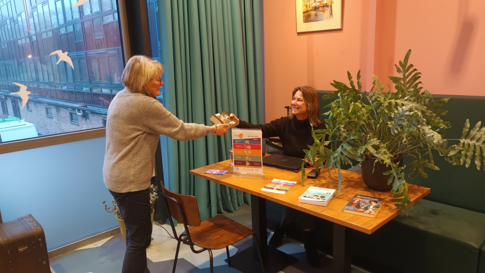 Een bewoner leent een boek bij het Biebpunt in 't Volle Hof