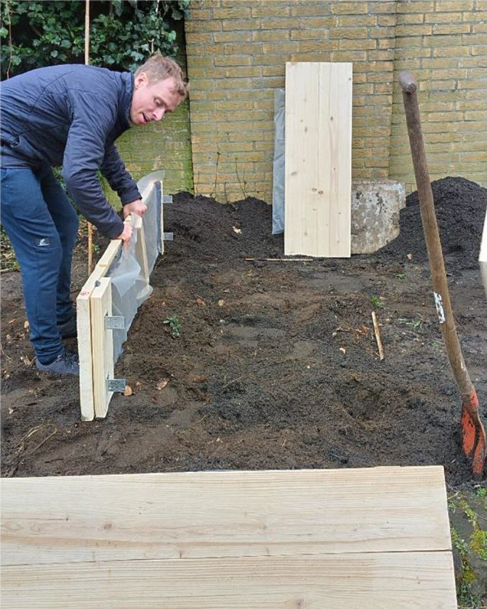 Bewoner die de moestuinbak aan het aanleggen is