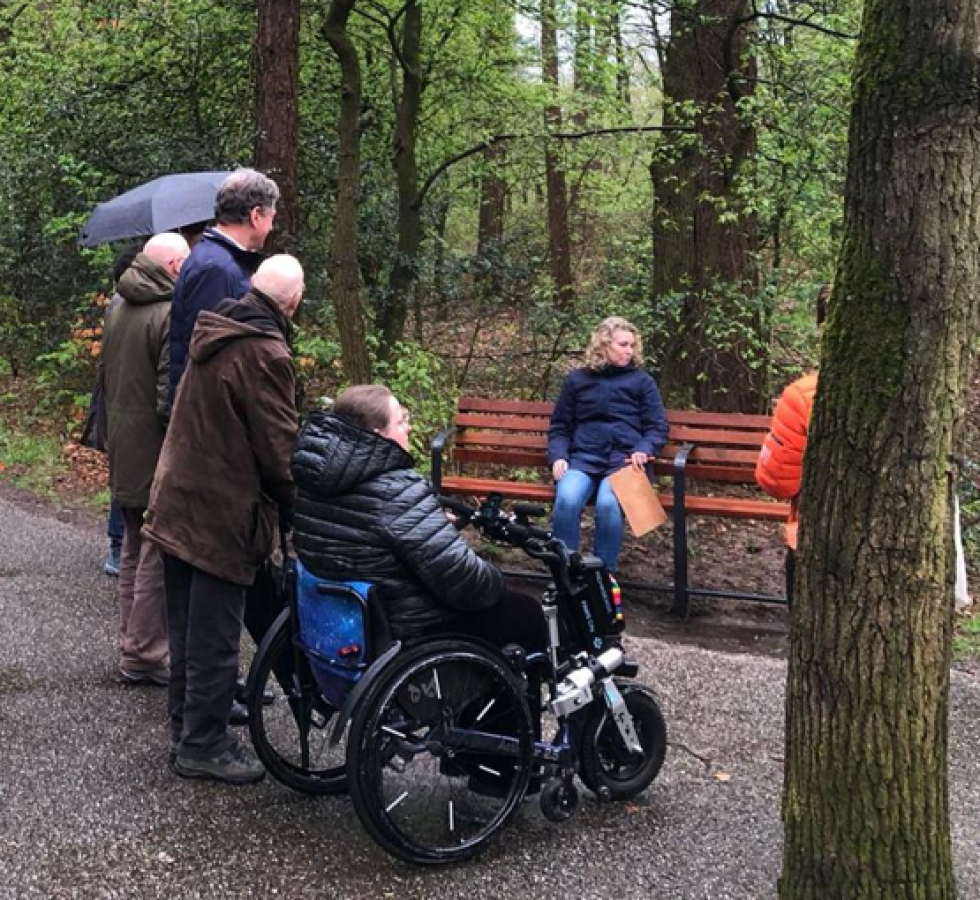 Bewoners tijdens de buurtwandeling op 5 april. Enkele bewoners staan in het pad naar het park en anderen zitten op een bankje.