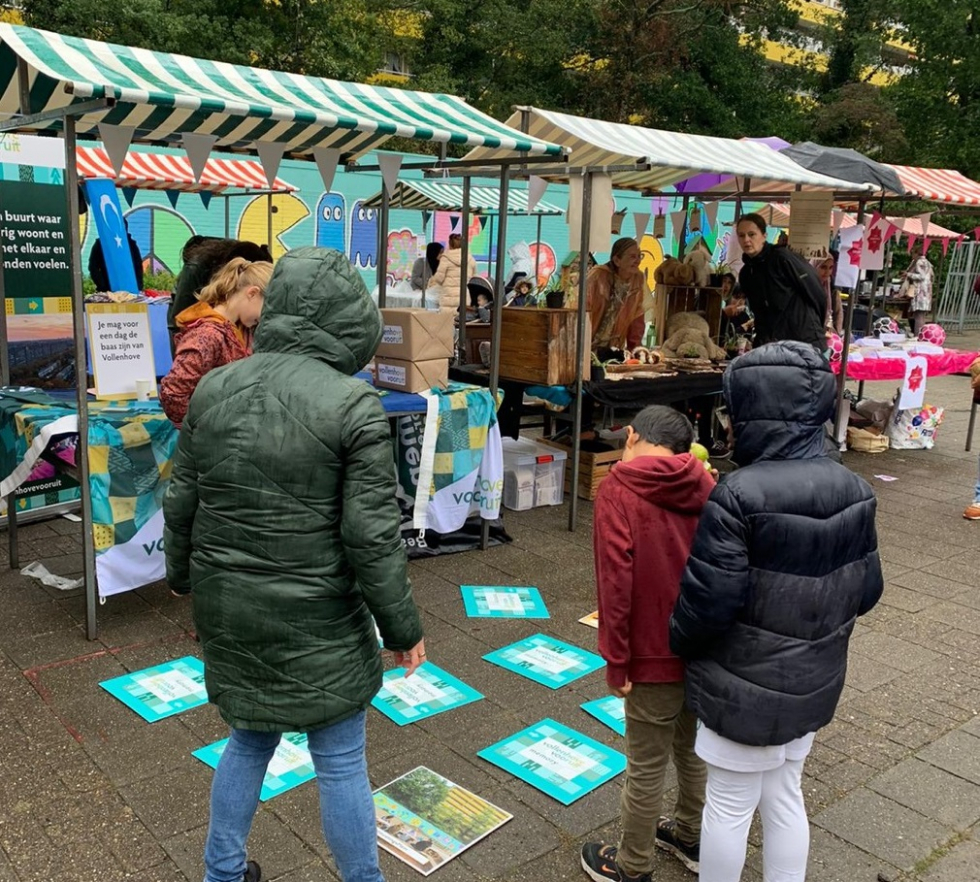 Kinderen die het memoryspel spelen bij de Vollenhove Vooruit kraam tijdens het Buurtfeest. Er liggen verschillende memorystukken op de grond. 