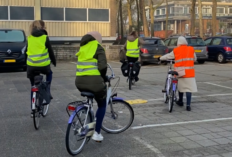 Vier vrouwen op hun fiets tijdens de fietslessen met een een geel of oranje hesje aan