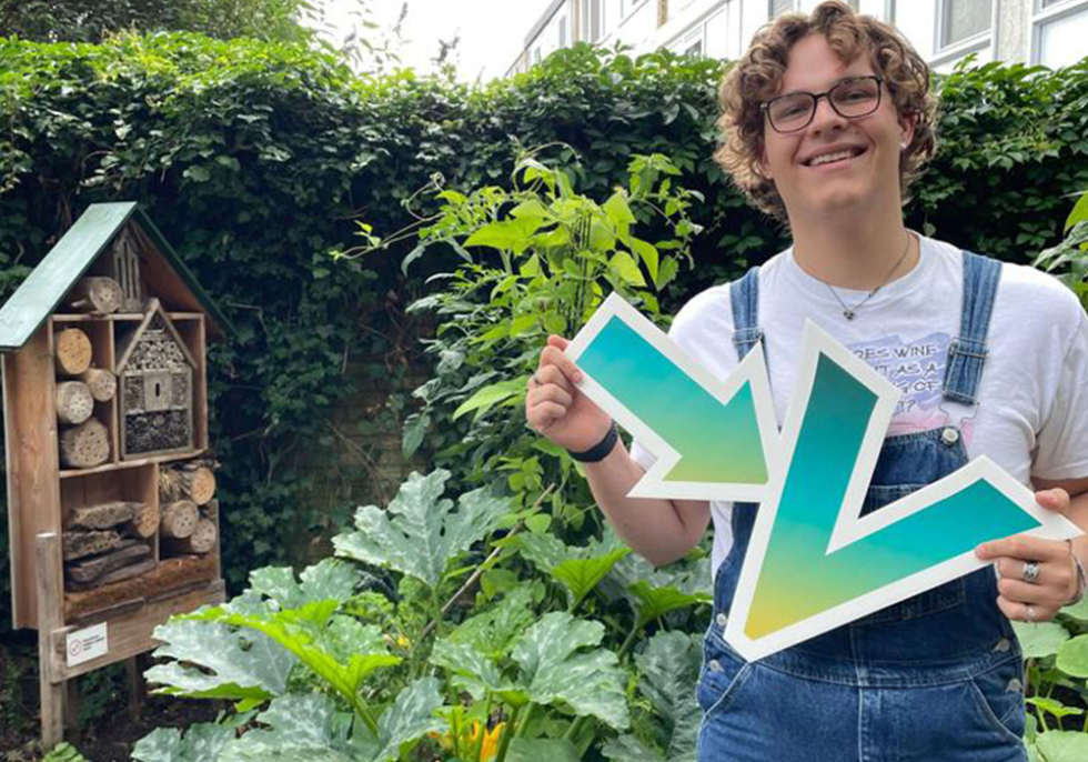 Sander staat voor zijn moestuinbak met een bord in zijn hand met daarop een pijl en een V