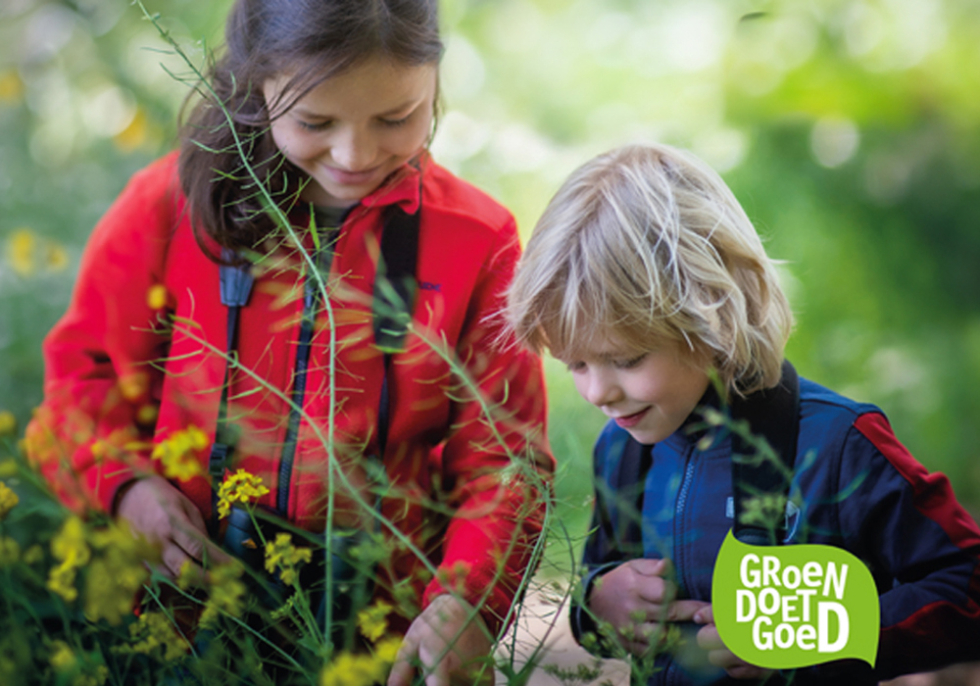 Twee kinderen kijken naar planten. Op de foto staat het groene logo van Groen Doet Goed festival.