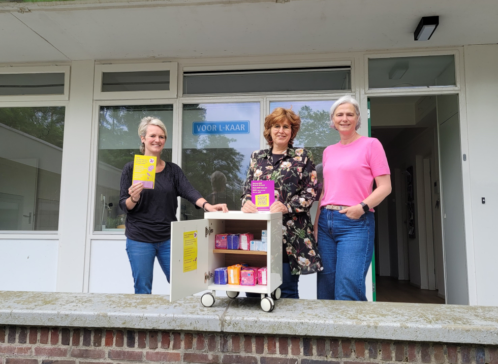 Rianna Verduin van het Wijkinloophuis samen met twee medewerkers van Voor L-kaar bij het menstruatie uitgiftepunt in Vollenhove