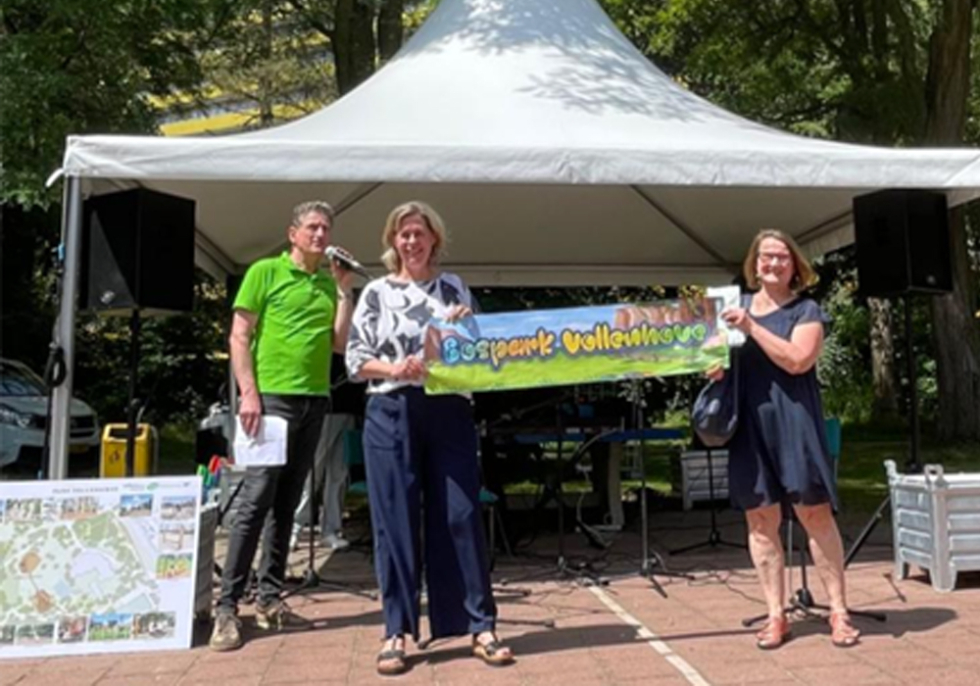 Een foto van de wethouder, programmamanager van Vollenhove Vooruit en nog een derde persoon die samen de banner met de nieuwe naam Bospark Vollenhove vasthebben.