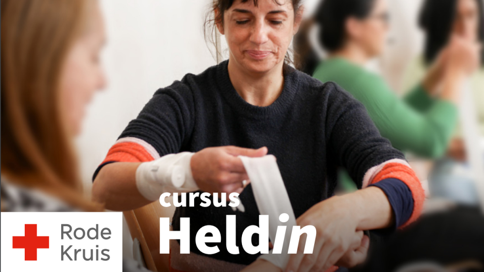 Een foto van een vrouw die verband omlegt bij een andere vrouw. Op de foto staat ook de tekst 'Cursus Heldin' en het logo van Het Rode Kruis