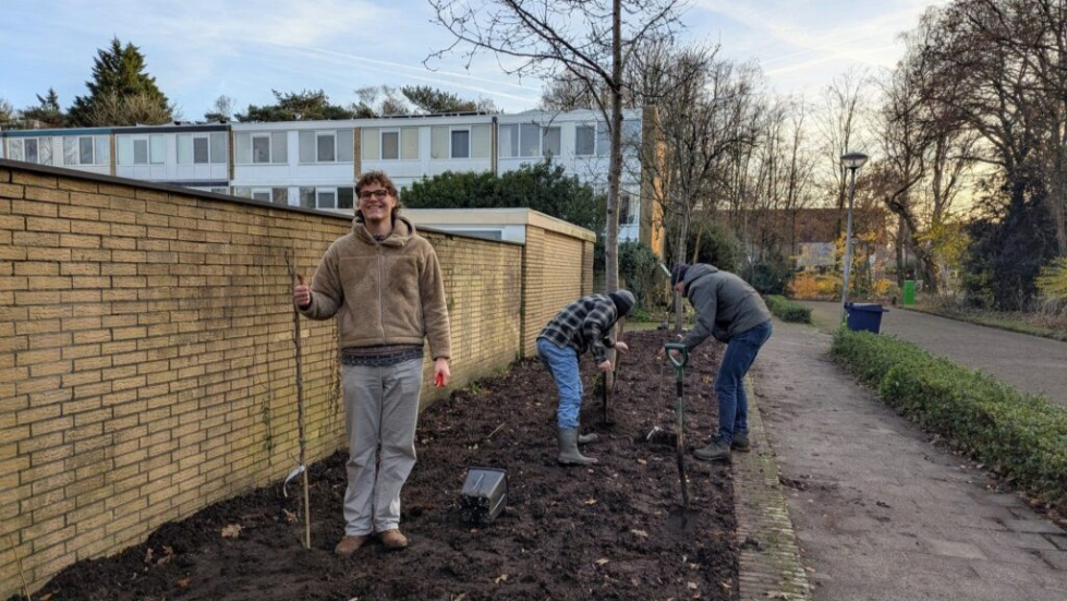 Bewoner Sander staat trots in de tuin aan de Fröbellaan. Op de achtergrond zijn twee andere bewoners aan het werk. 