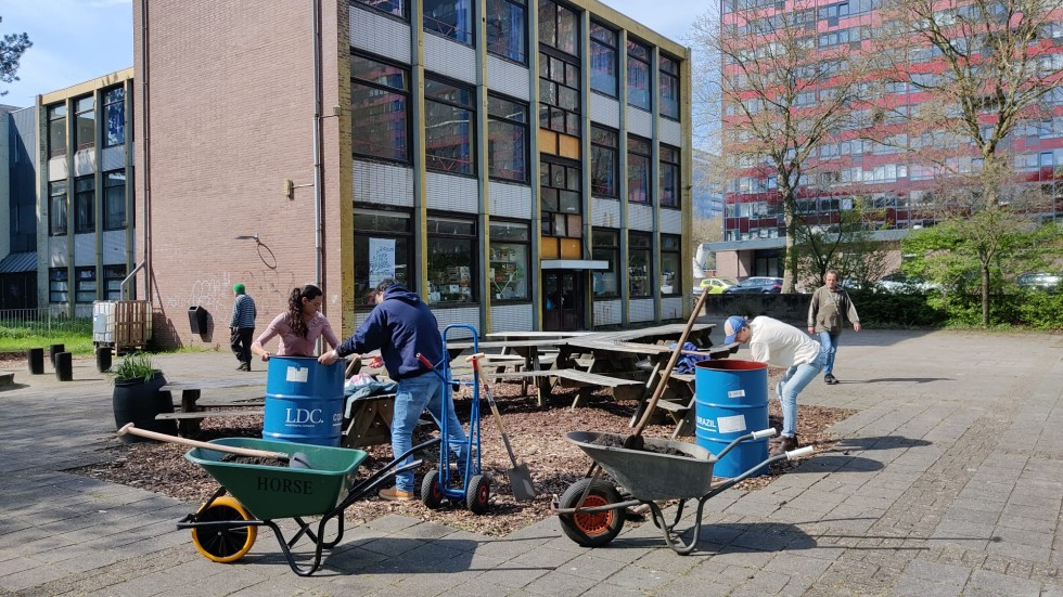 Foto de Groengroep die aan het werk is op het ontmoetingsplein bij de boomtafel