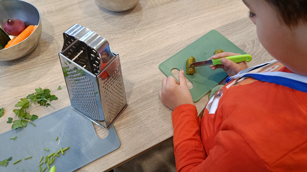 Foto van een leerling die eten aan het snijden is