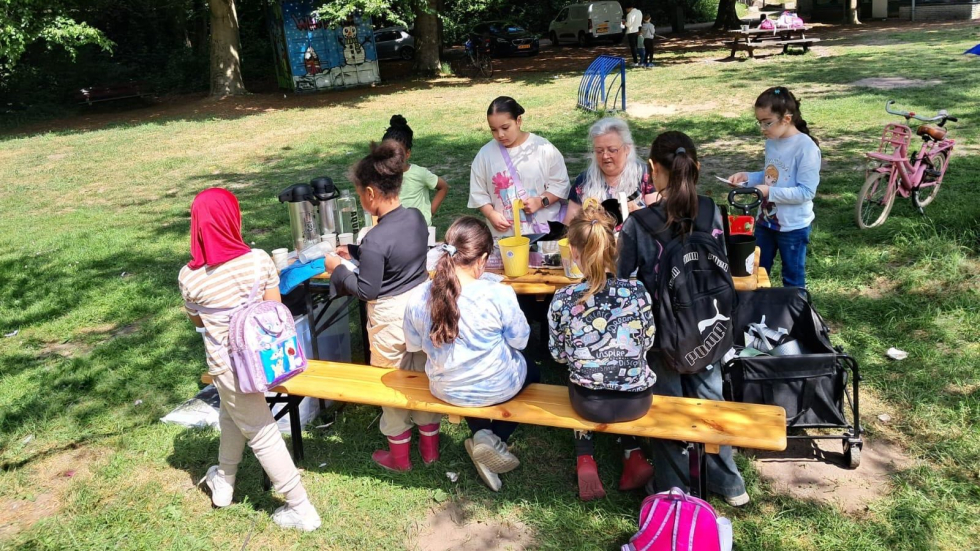 Veel kinderen aan een picknicktafel in het Bospark