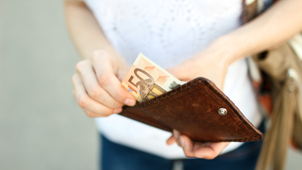 Foto van iemand die een biljet van €50 uit een portemonnee haalt 