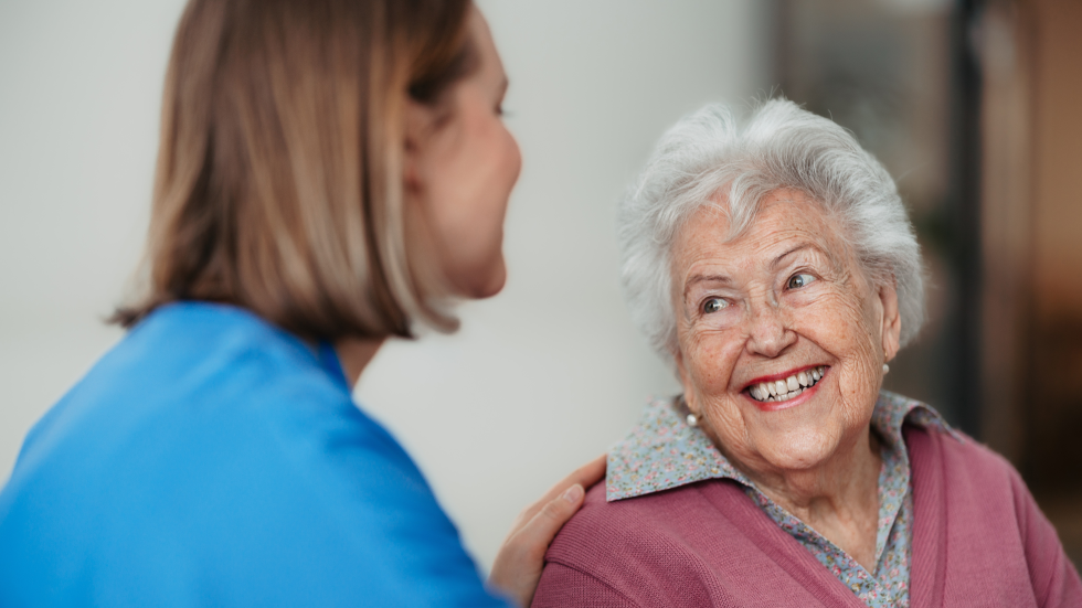 Een foto van een oudere vrouw die lacht naar een jongere vrouw