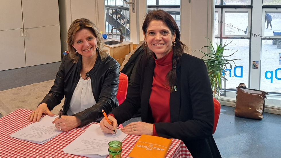 Een foto van Mascha van Werven, directeur van Jantje Beton en Angele Welting, wethouder van gemeente Zeist samen aan tafel waar ze een contract tekenen. 