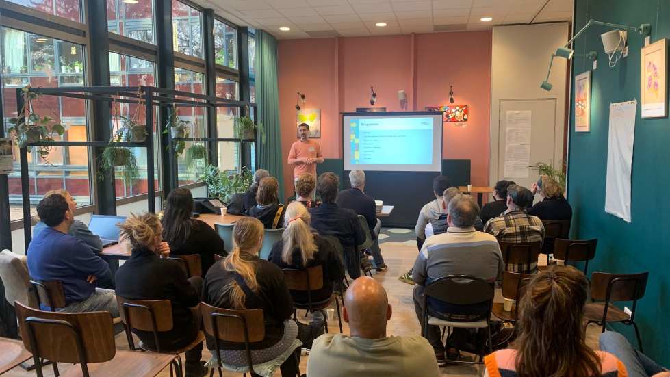 Groep bewoners kijkt naar een presentatiescherm in wijkcentrum 't Volle Hof